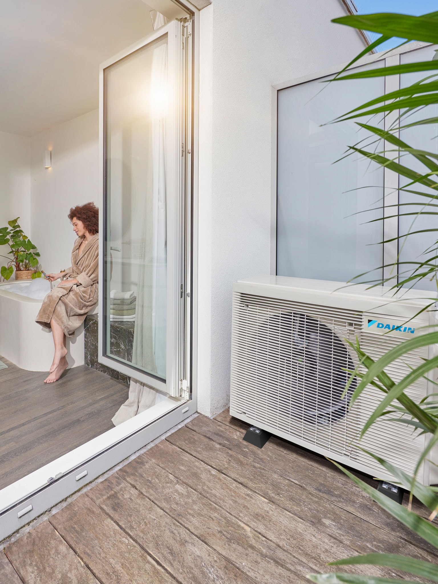 Luft-Wärmepumpe, installiert neben der Terrasse mit offenen Türen zu einem modernen Badezimmer