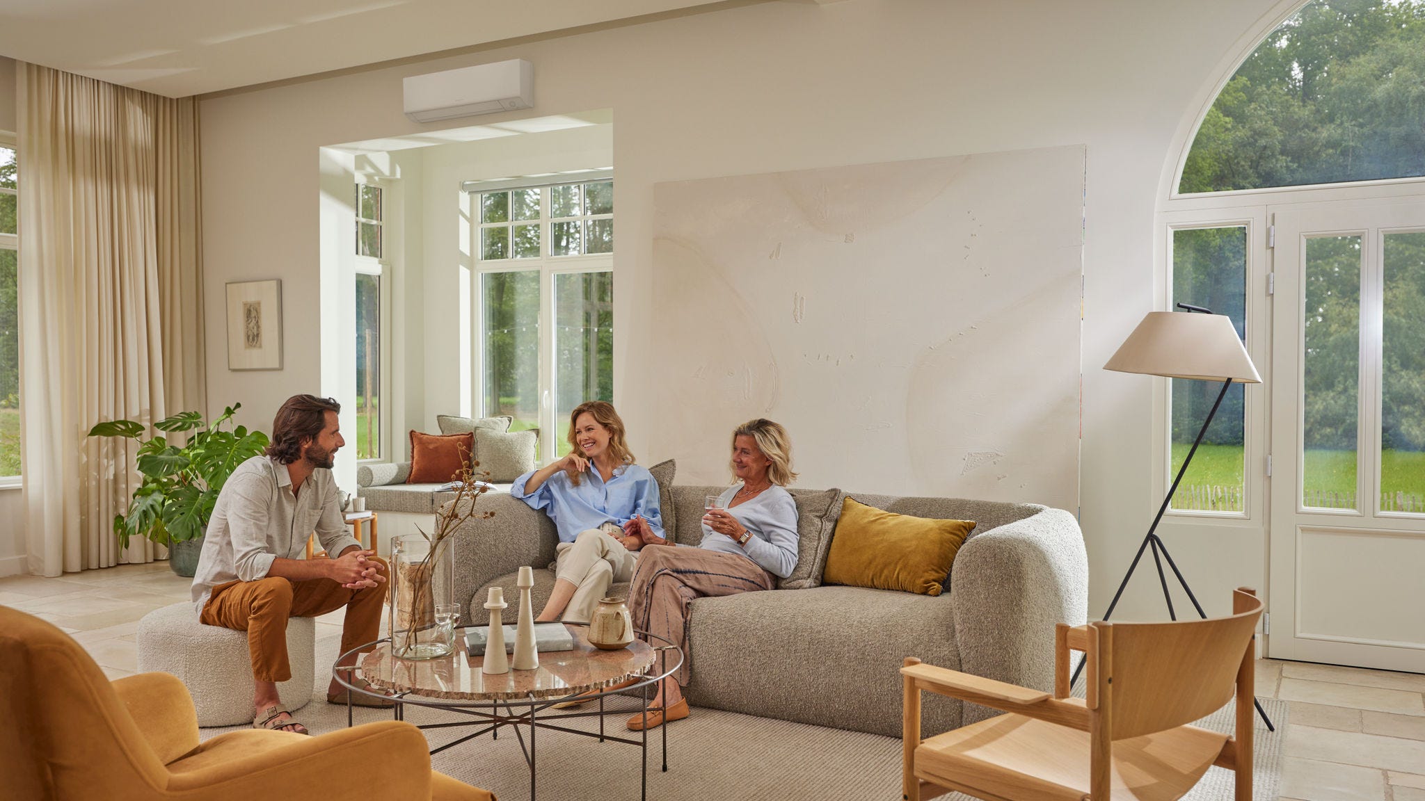 Familie entspannt sich im Wohnzimmer mit einer an der Wand montierten Klimaanlage