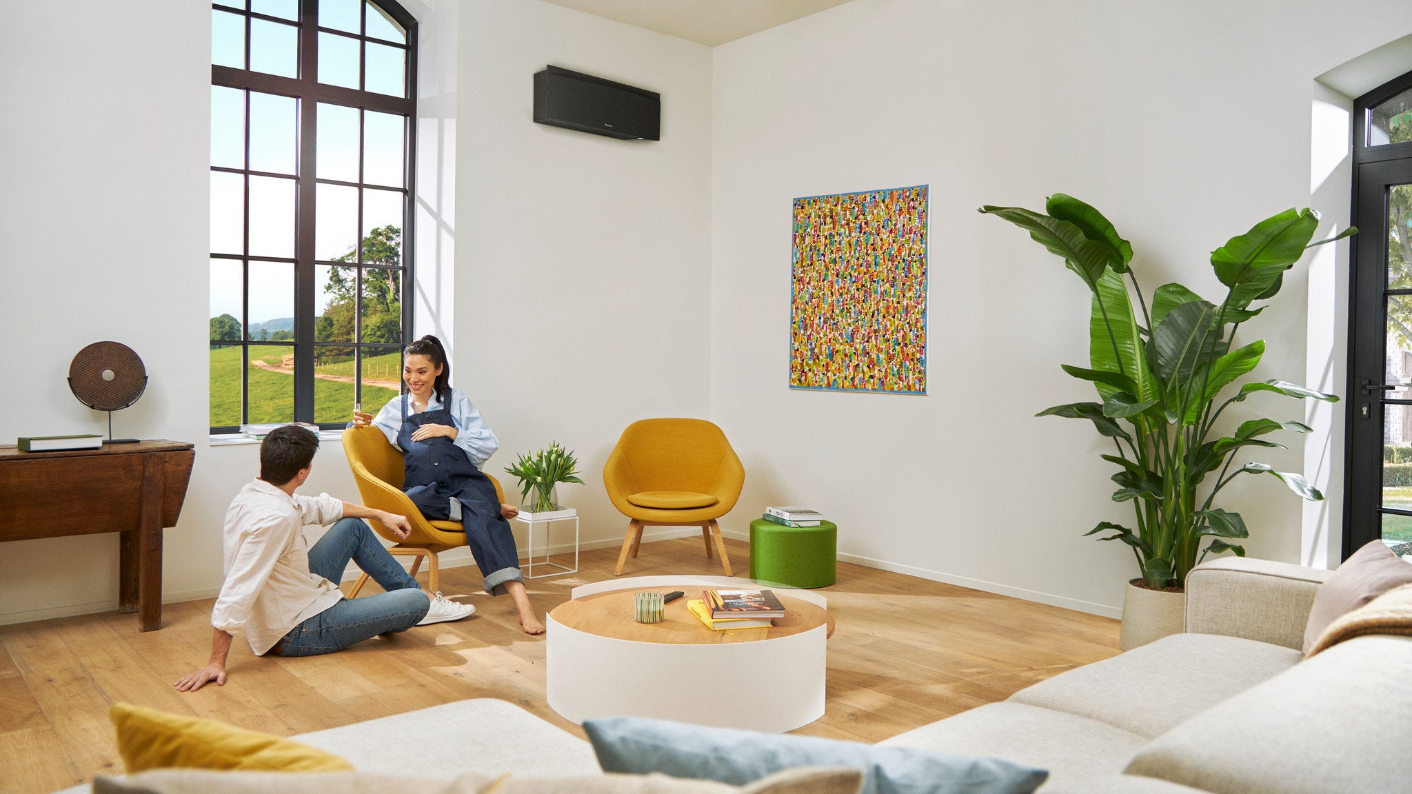 Ein schwangeres Paar unterhält sich, die Frau sitzt auf einem Stuhl.