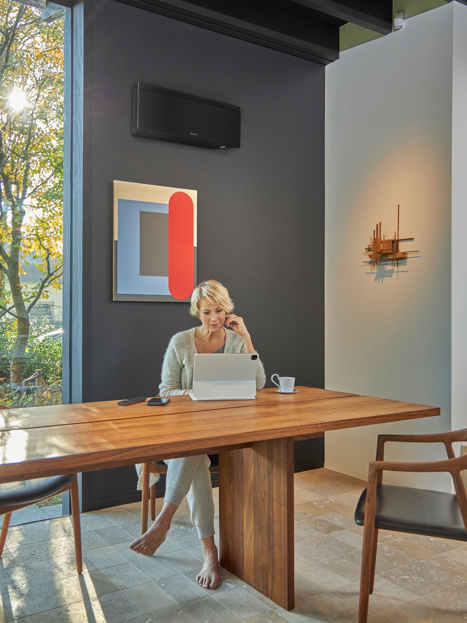 Frau mit einem Tablet im Esszimmer, mit einer an der Wand montierten Klimaanlage