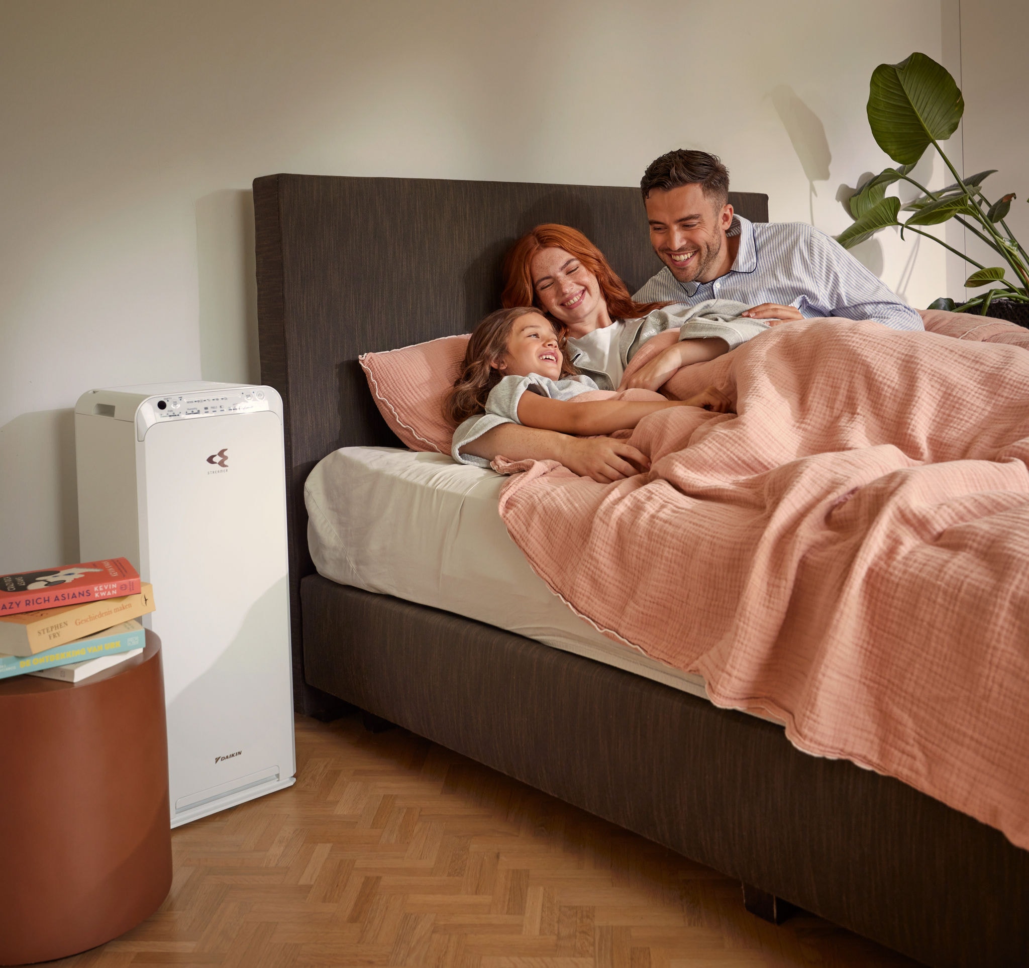 Ein Paar mit Kind entspannt sich im Schlafzimmer und genießt die durch einen Luftreiniger gereinigte Luft