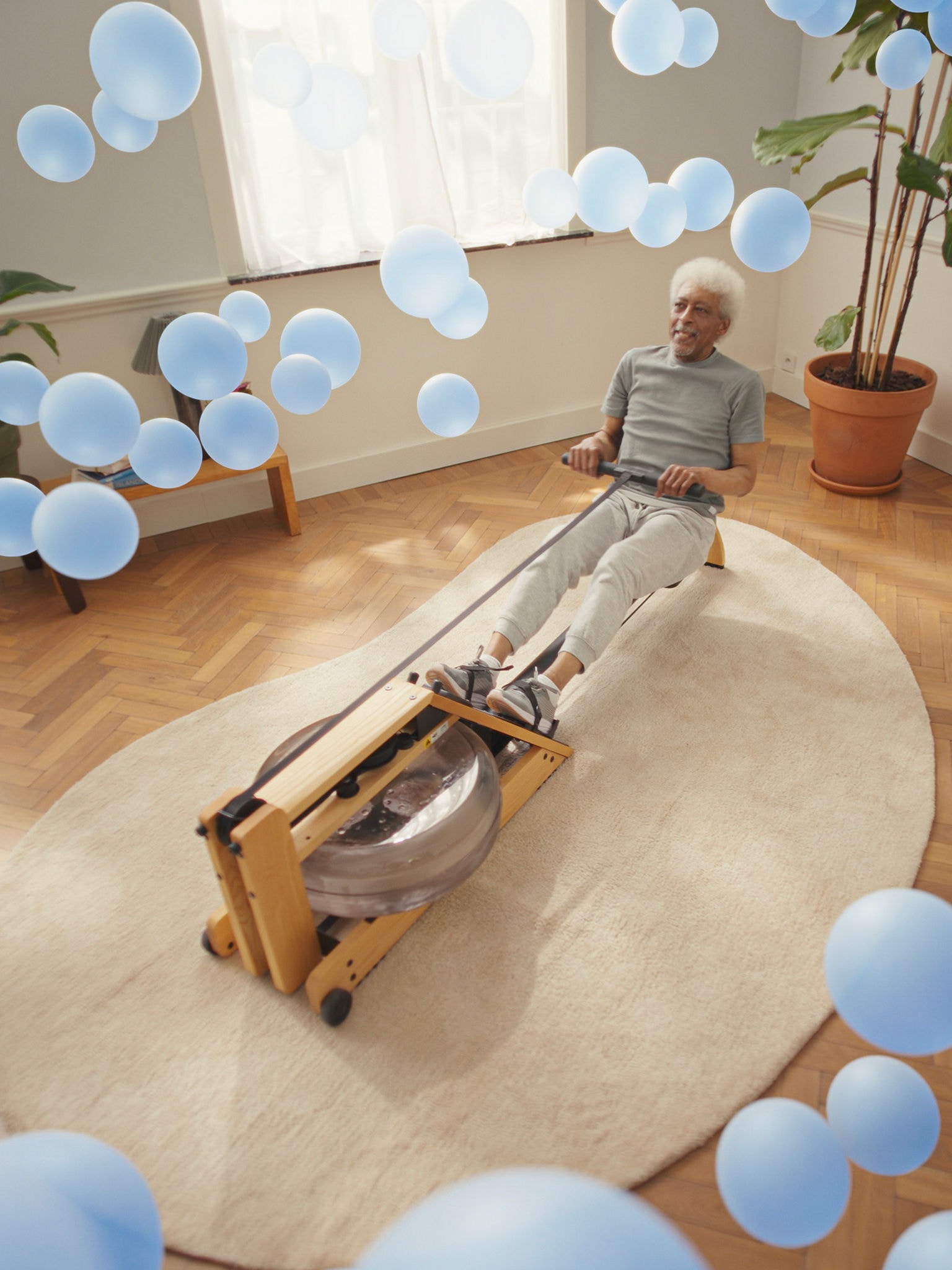 Ein älterer Mann trainiert an einem Rudergerät in einem, dank der reaktionsschnellen Luft-Luft-Wärmepumpentechnologie, perfekt klimatisierten Raum