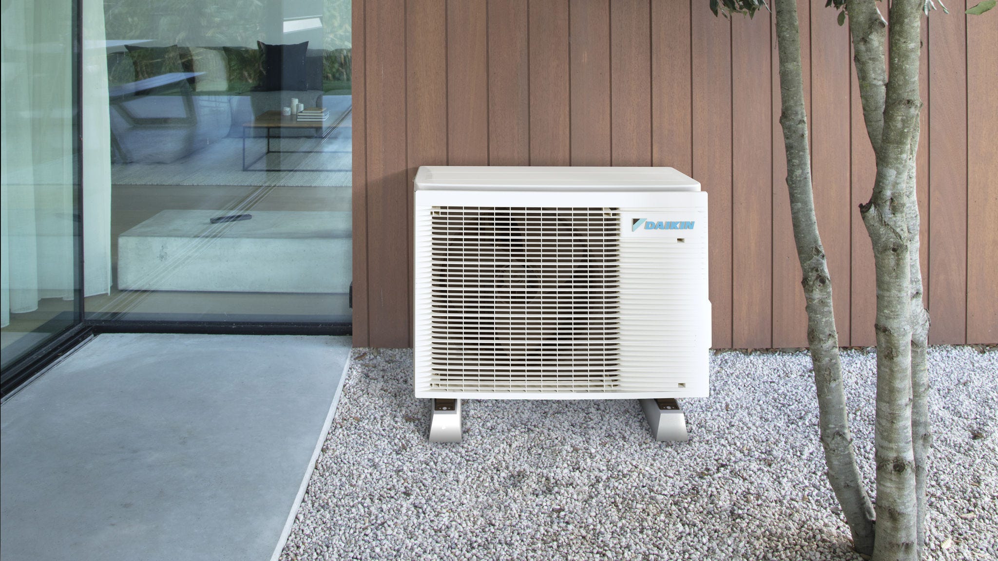 Kompakte Luft-Wärmepumpe, unauffällig im Außenbereich neben einem modernen Wohnhaus installiert