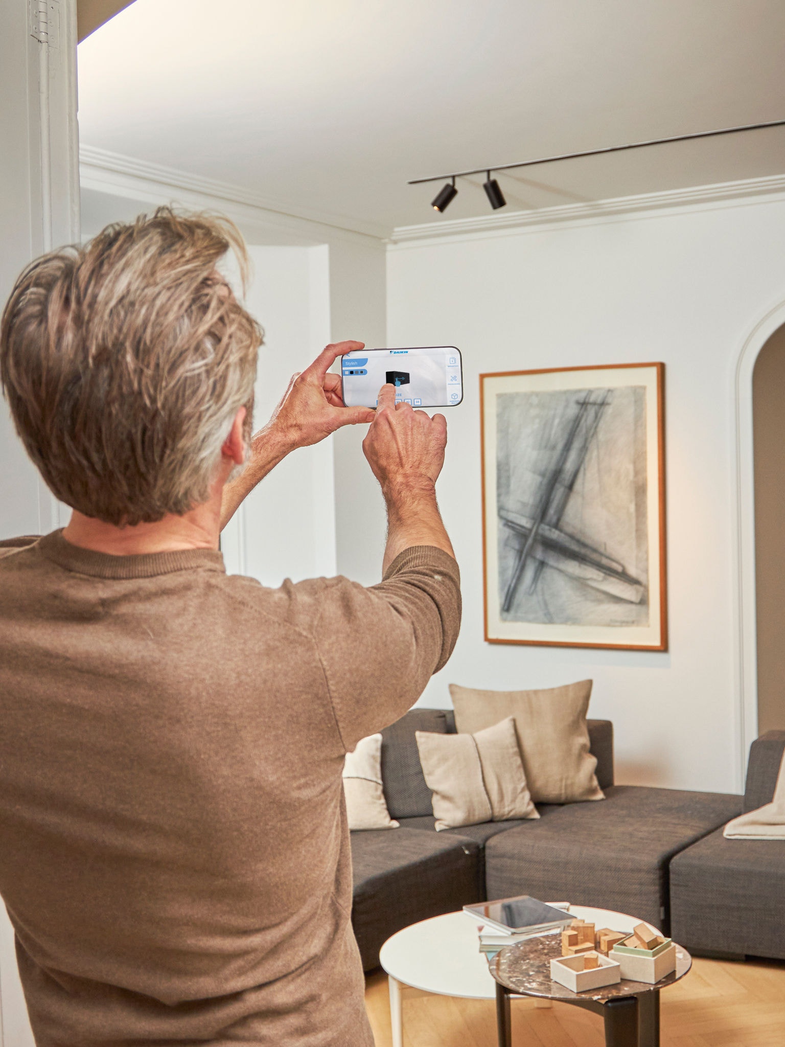 Ein Mann betrachtet anhand der 3D-App mit erweiterter Realität für Luft-Luft-Wärmepumpen die Geräte mit Innen- und Außendesign.