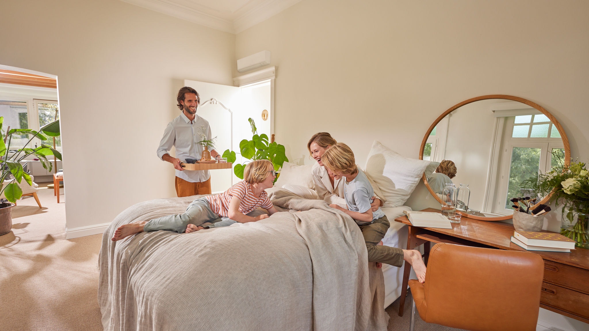 Eine Familie genießt in einem Schlafzimmer mit einem Wandgerät der Hybrid-Wärmepumpe einen ruhigen Augenblick