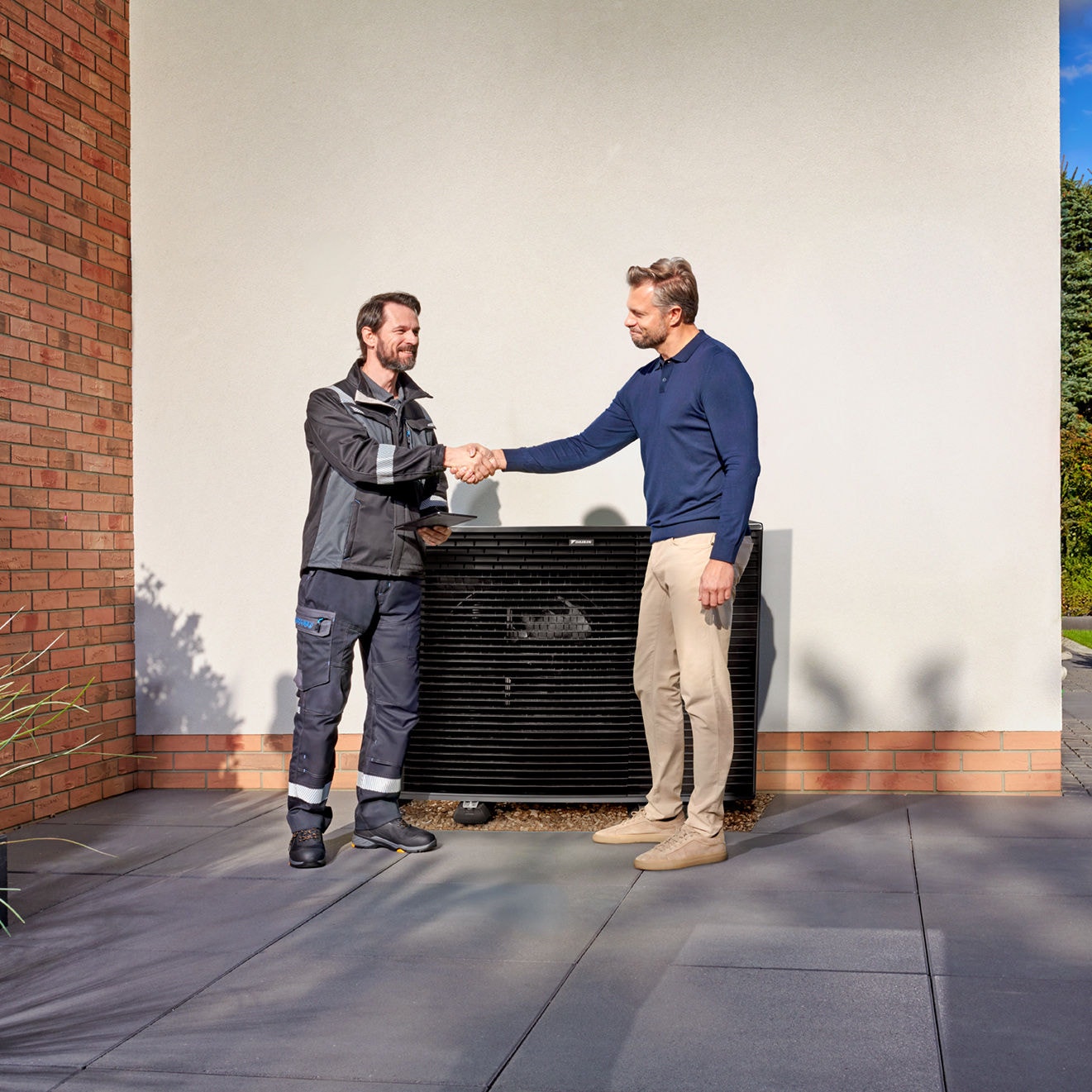 Techniker und Kunde beim Handschlag vor einer installierten DAIKIN Wärmepumpe – Symbol für professionelle Beratung und zuverlässigen Service.