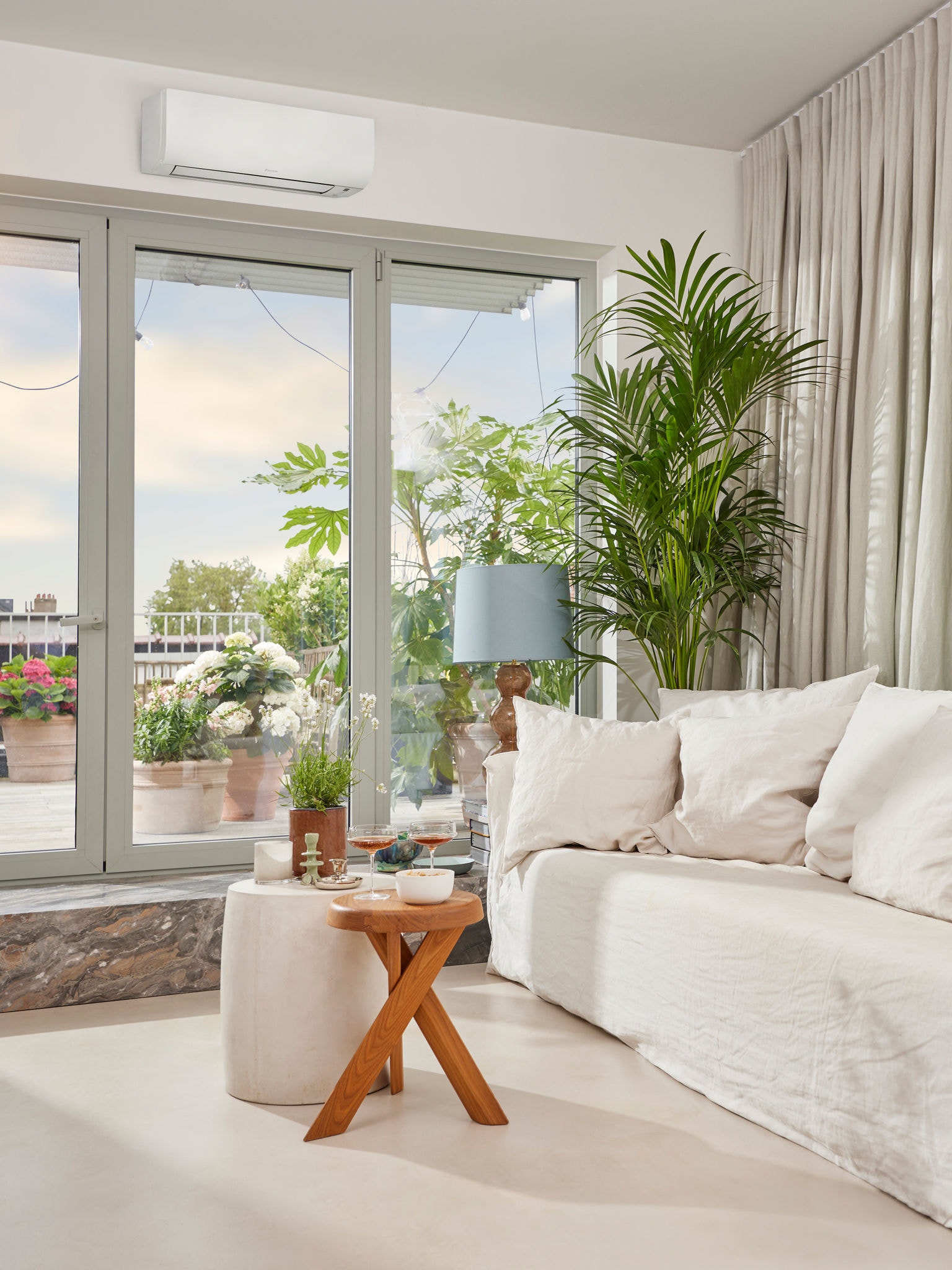 Helles, gemütliches Wohnzimmer mit einer Bar-Ecke, große Glastüren zur Terrasse, über einer befindet sich eine Klimaanlage.