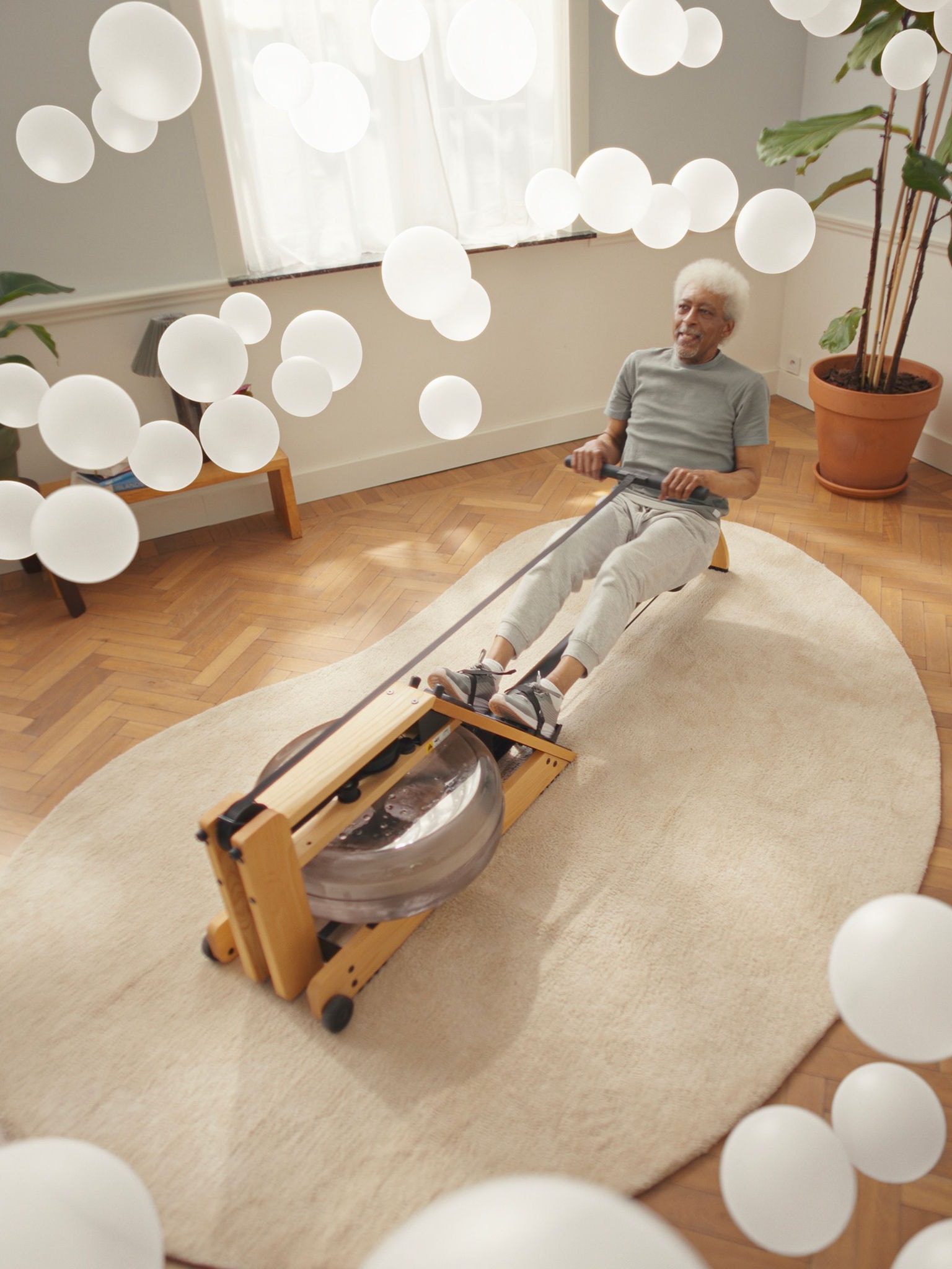 Älterer Mann beim Training auf einem Rudergerät in einem Raum mit, dank Luftreiniger, sehr sauberer Luft