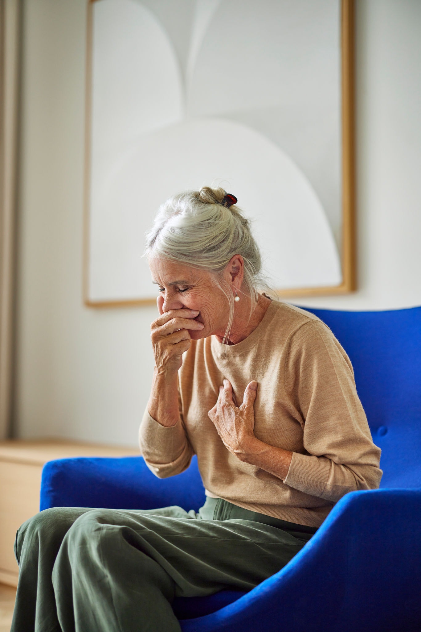 Niesende Frau verdeutlicht die Notwendigkeit einer Lüftung für bessere Raumluftqualität und für eine Verringerung von Auslösern von Asthma