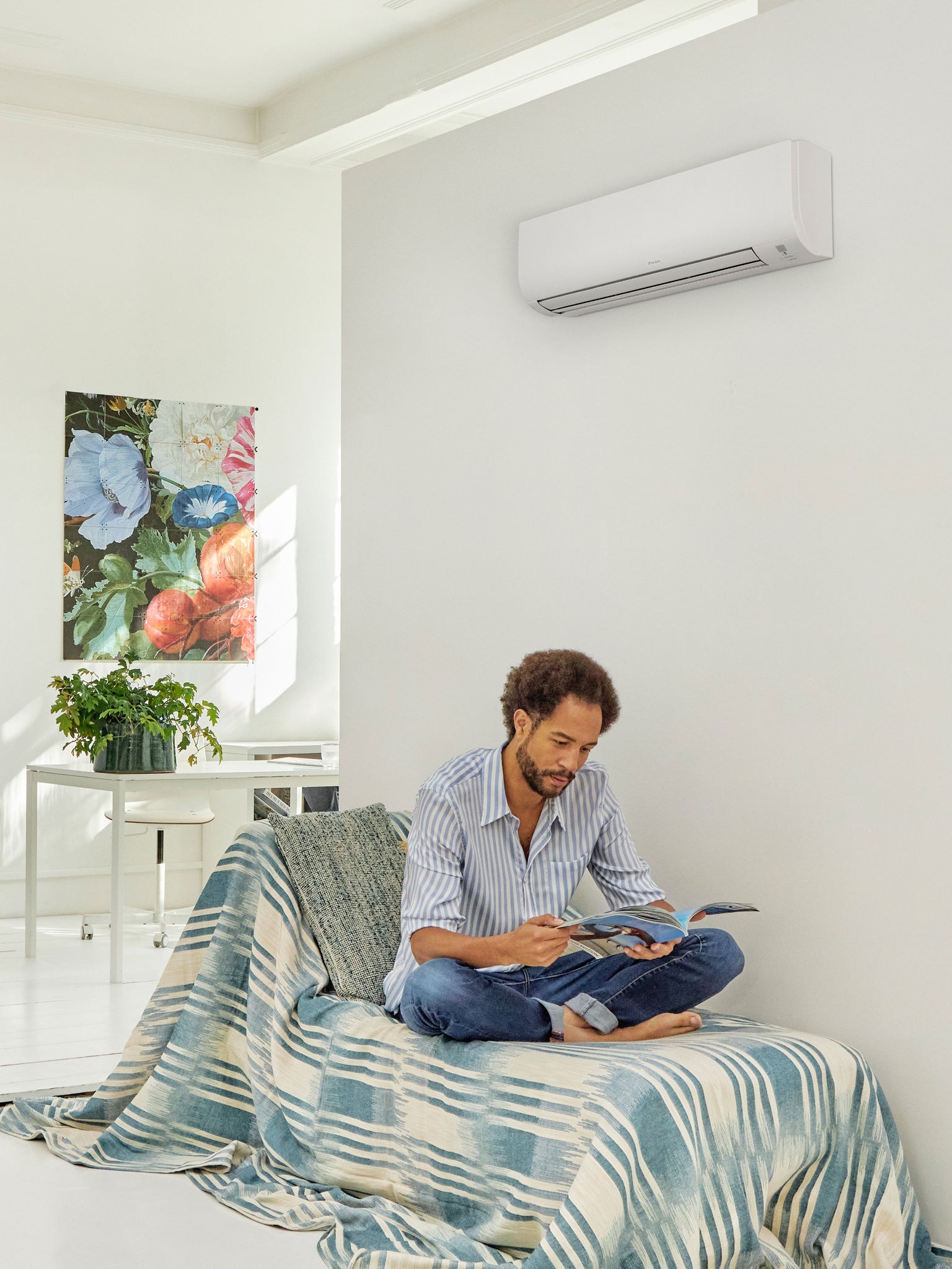 Mann liest in einem hellen, modernen Wohnzimmer mit Wärmepumpengerät an der Wand. Das verdeutlicht Komfort und Energieeffizienz der durch staatliche Förderprogramme unterstützte Wärmepumpentechnologien