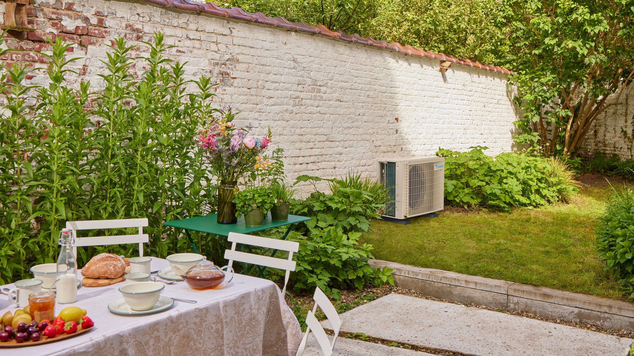 Frühstücksszene im Garten mit einer Inverter-Klimaanlage zur Kühlung des nahegelegenen Hauses