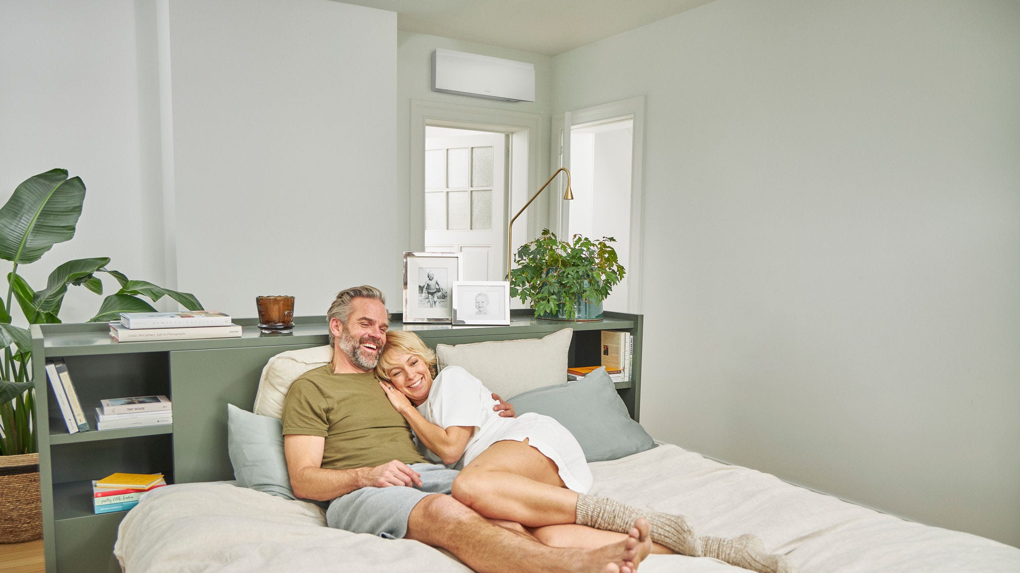 Ein Paar entspannt auf einem Bett in einem durch eine leise Klimaanlage gekühlten Schlafzimmer