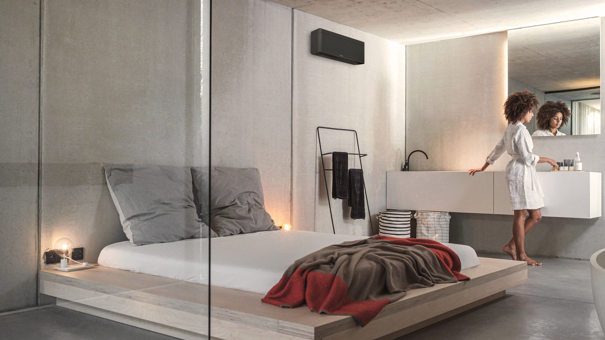 Eine Frau richtet sich in ihrem von einem Stylish Innengerät klimatisierten und geheizten Schlafzimmer mit Waschgelegenheit für den Tag her